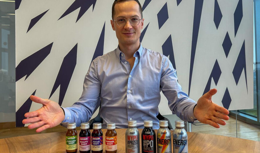 CEO of Chias Brothers presenting a lineup of functional shots including ginger, turmeric, energy and focus drinks, sitting at a table in a modern office setting.