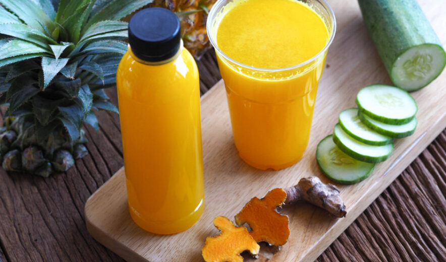Turmeric and pineapple wellness shot with cucumber – natural detox juice in bottle and glass