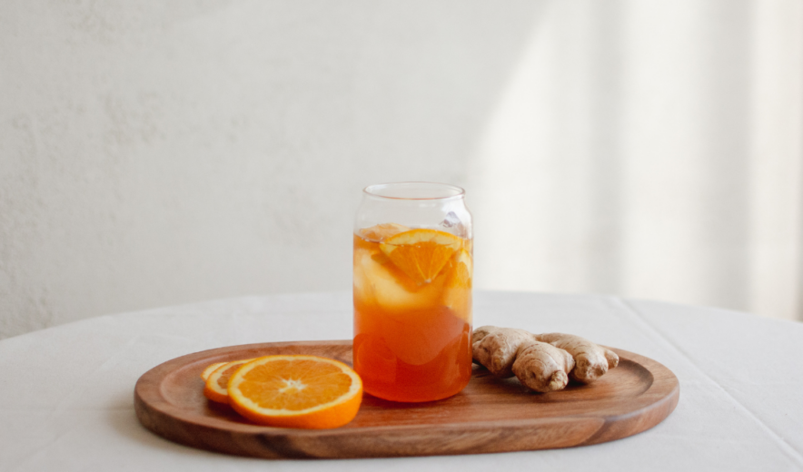 Glass of orange and ginger juice on a wooden tray – natural energy shot with vitamin C and antioxidants