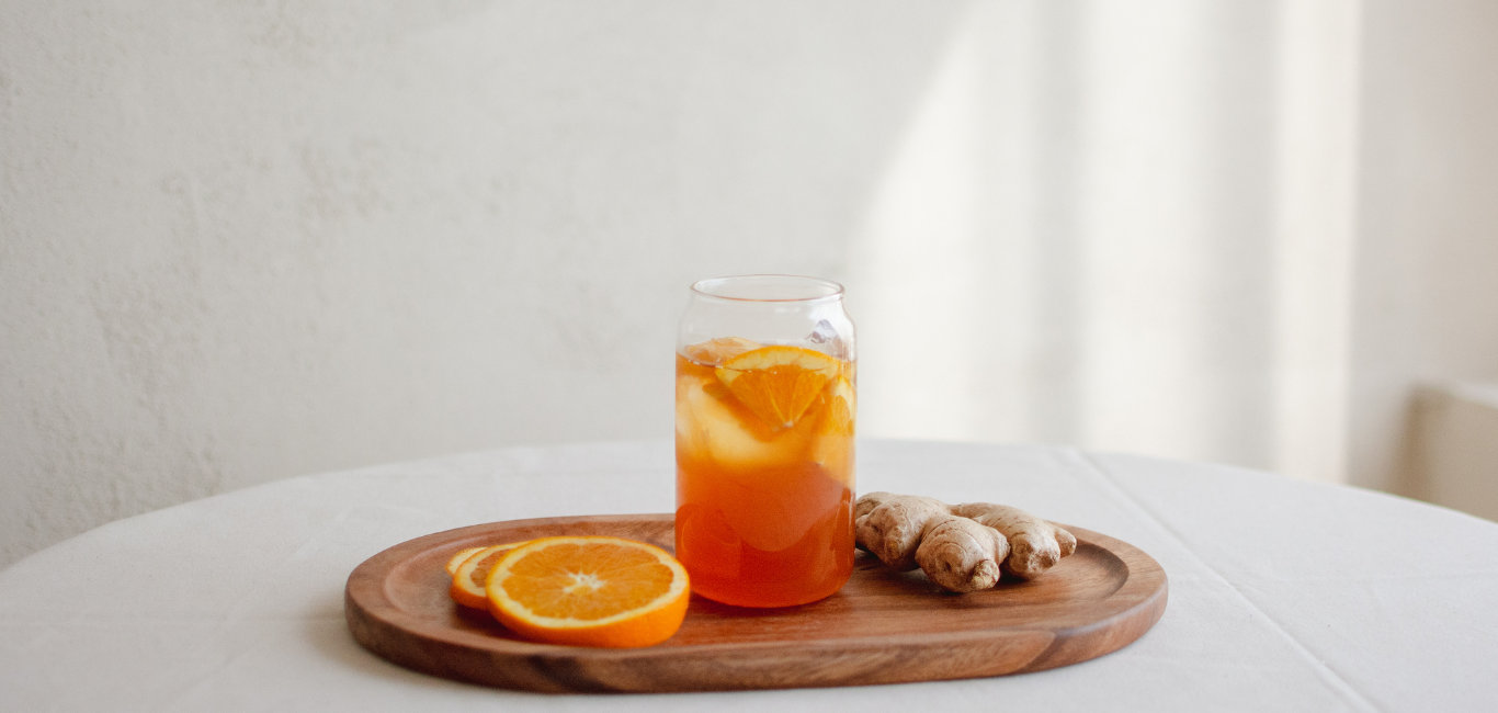 Glass of orange and ginger juice on a wooden tray – natural energy shot with vitamin C and antioxidants