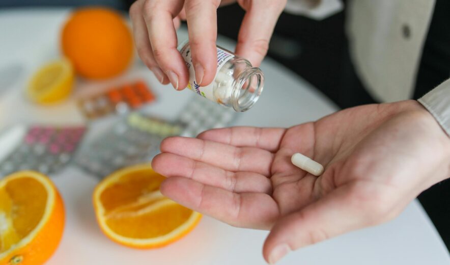 Taking a dietary supplement capsule – natural vitamin boost with citrus in the background