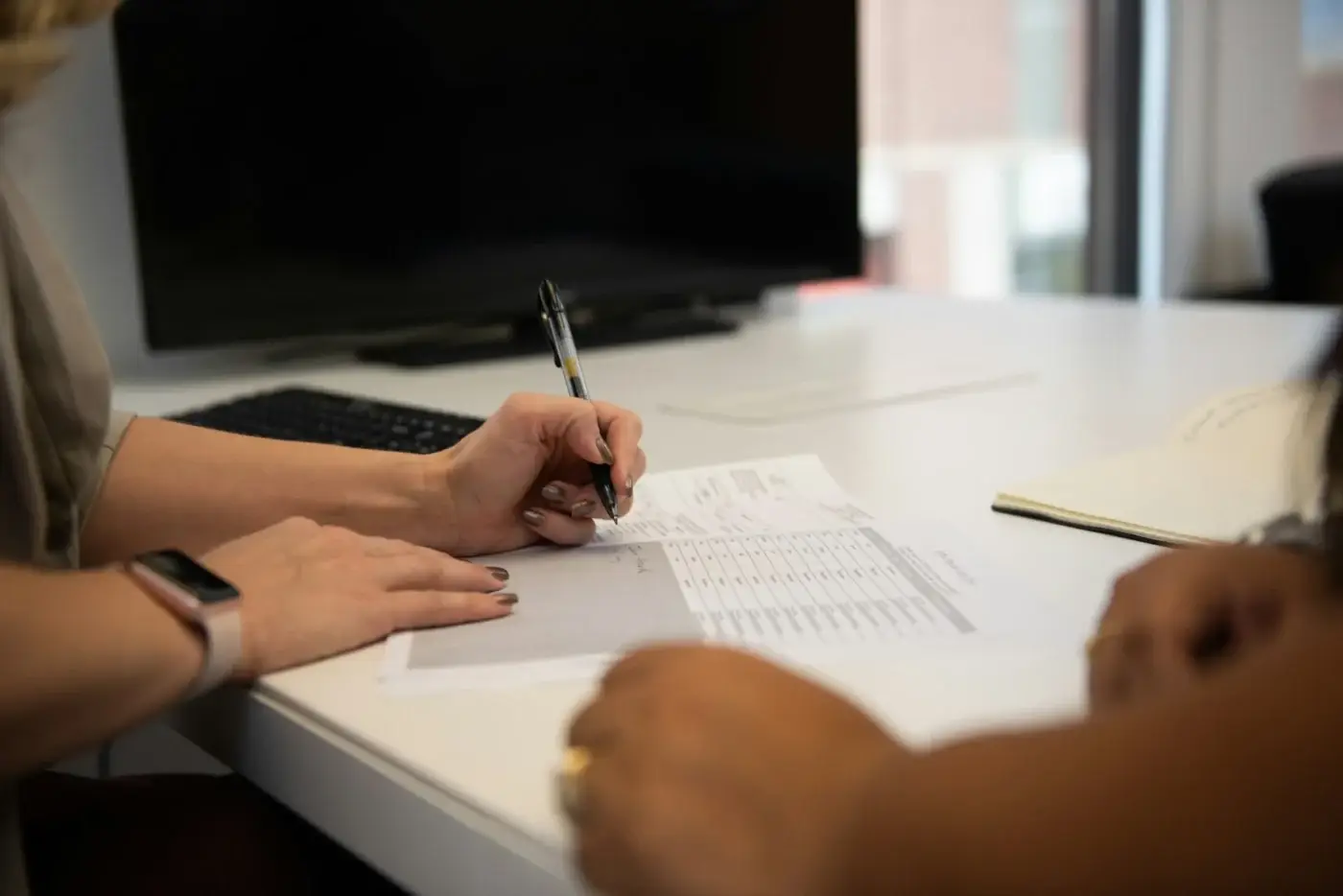 Two people reviewing a printed due diligence checklist at an office desk