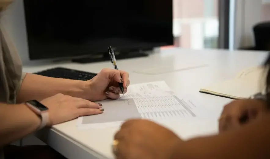 Two people reviewing a printed due diligence checklist at an office desk
